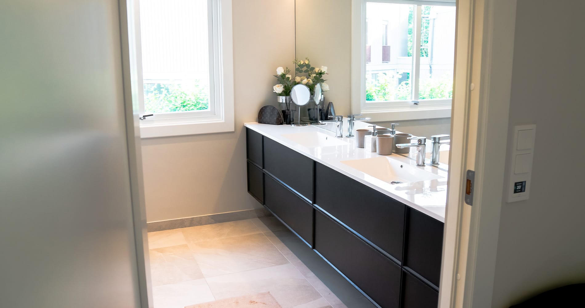 Lyst og moderne hovedbad hjemme hos Celina Olsson med dobbelservant, stort speil og detaljer i krom.