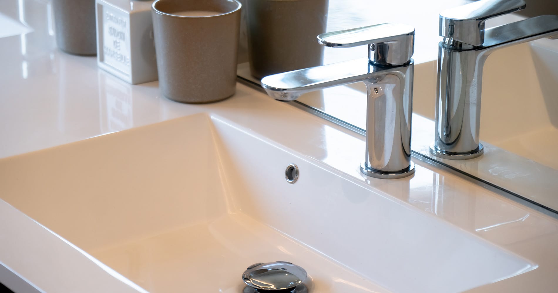 Moderne baderom med varme beige flater, mørkt treverk og detaljer i krom.